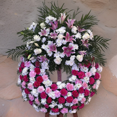 Corona funeraria en tonos rosas con claveles, rosas y flor variada
